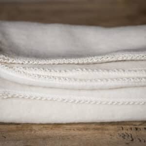 Merino-Wollfleece-Babydecke mit einem feinen Rand aus Mäusezähnchen in natur