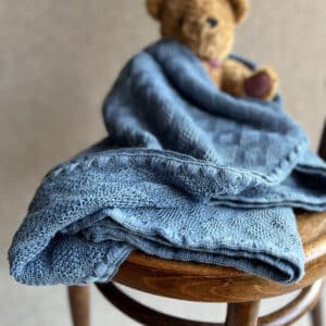 Disana Babydecke aus Merinoschurwolle mit einem Ajourstrickmuster in blau